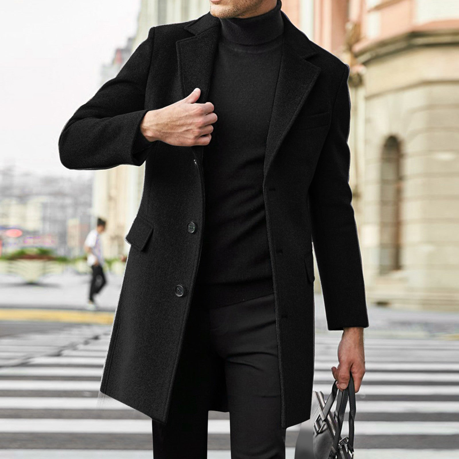 Person wearing a black coat and turtleneck standing on a city street.